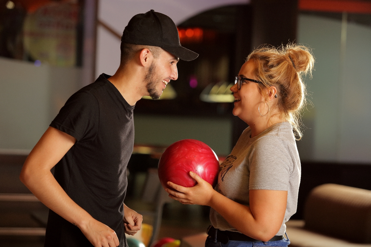 man and woman standing together chatting holding bowling balls