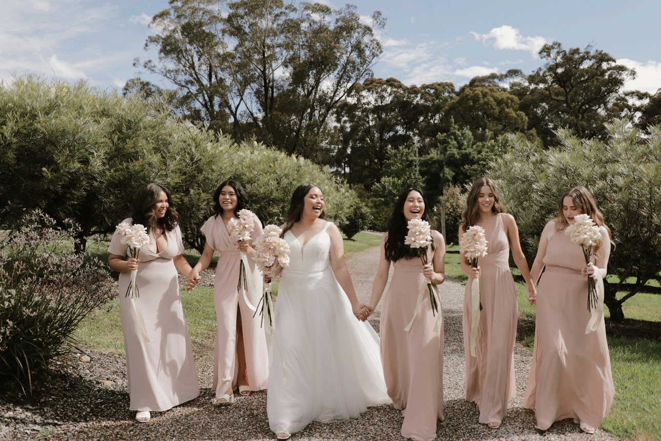 bride and bridesmaids on sunny day walking through garden