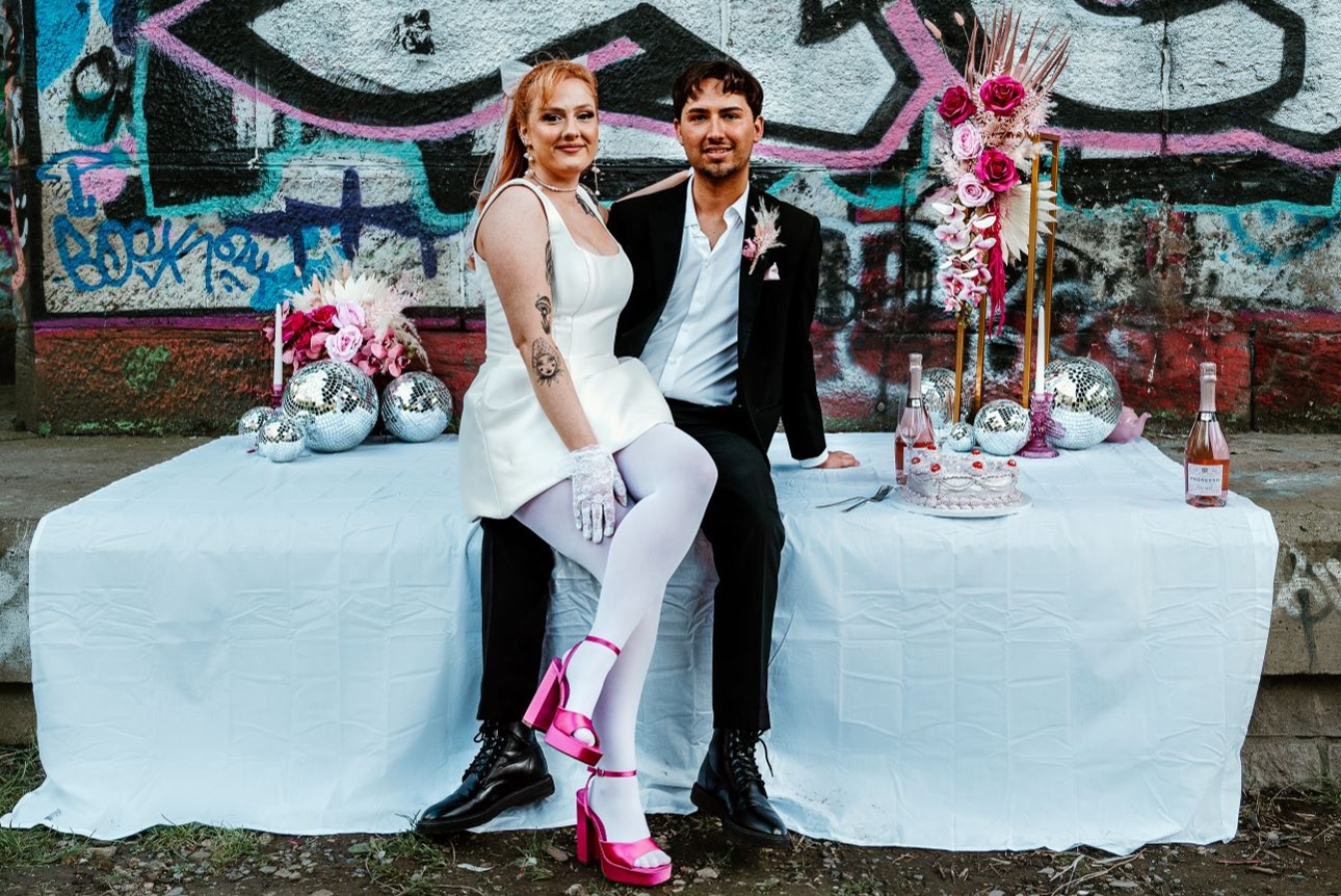 retro styled wedding couple in front of graffiti wall on wedding table