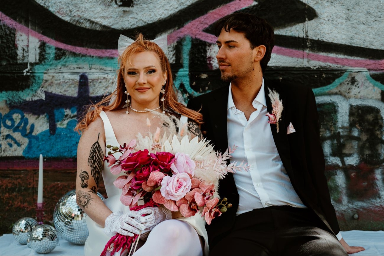 retro styled wedding couple in front of graffiti wall 