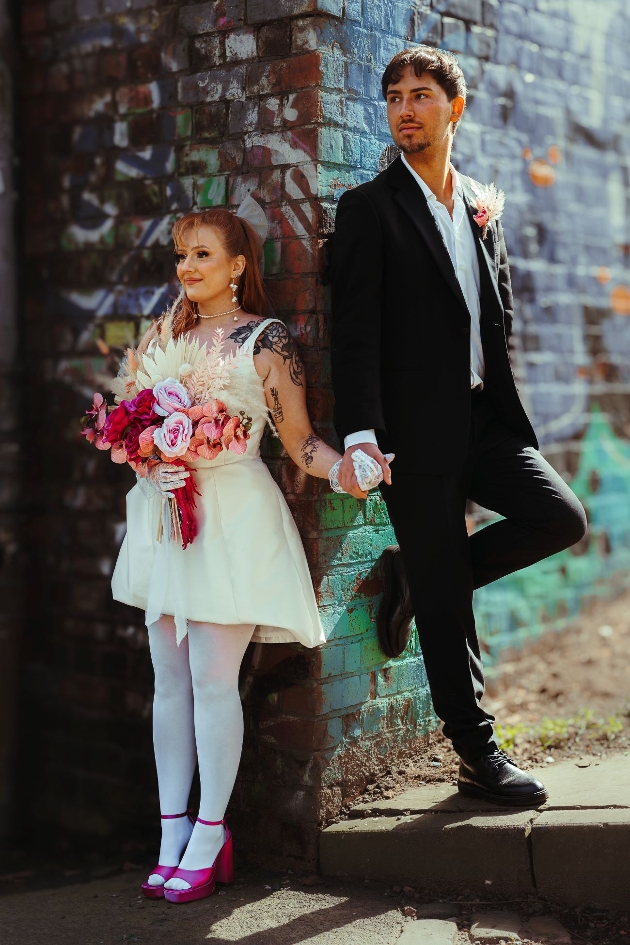 retro styled wedding couple in front of graffiti wall back to back