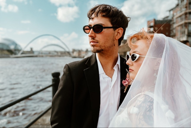 retro styled wedding couple in front of bridge looking at river