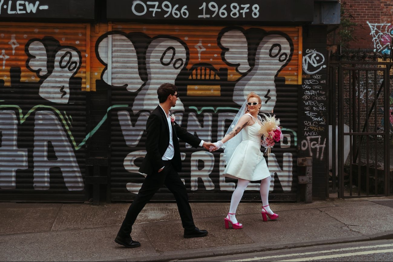 retro styled wedding couple in front of graffiti wall shop shutters in street