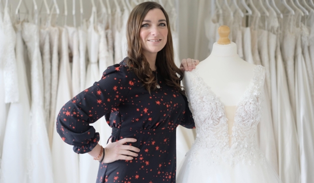 bridal shop manager standing with rail of dresses