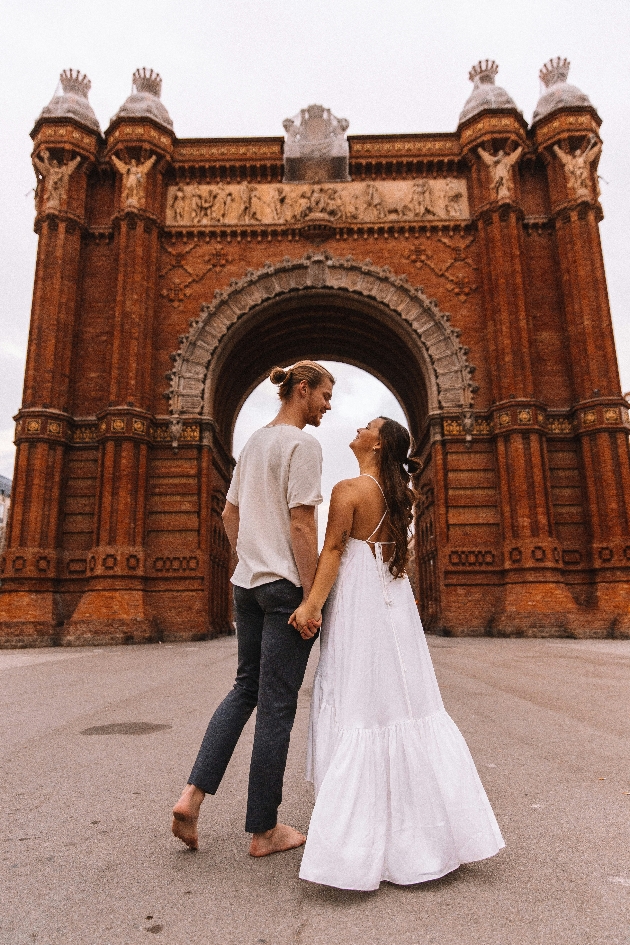 A man and woman standing hand-in-hand in front of a large gate