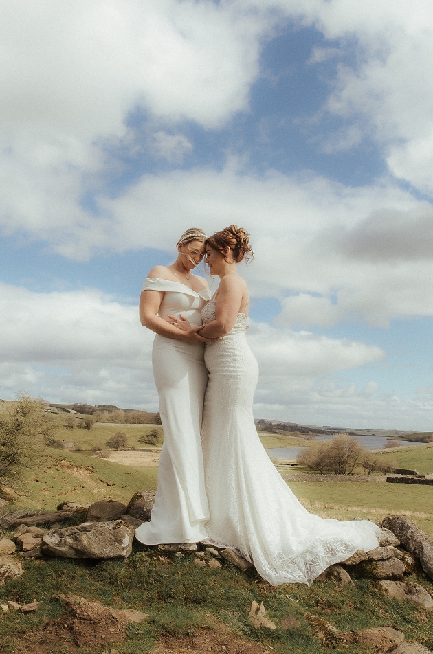 two brides in dresses on the rocks on the hillside