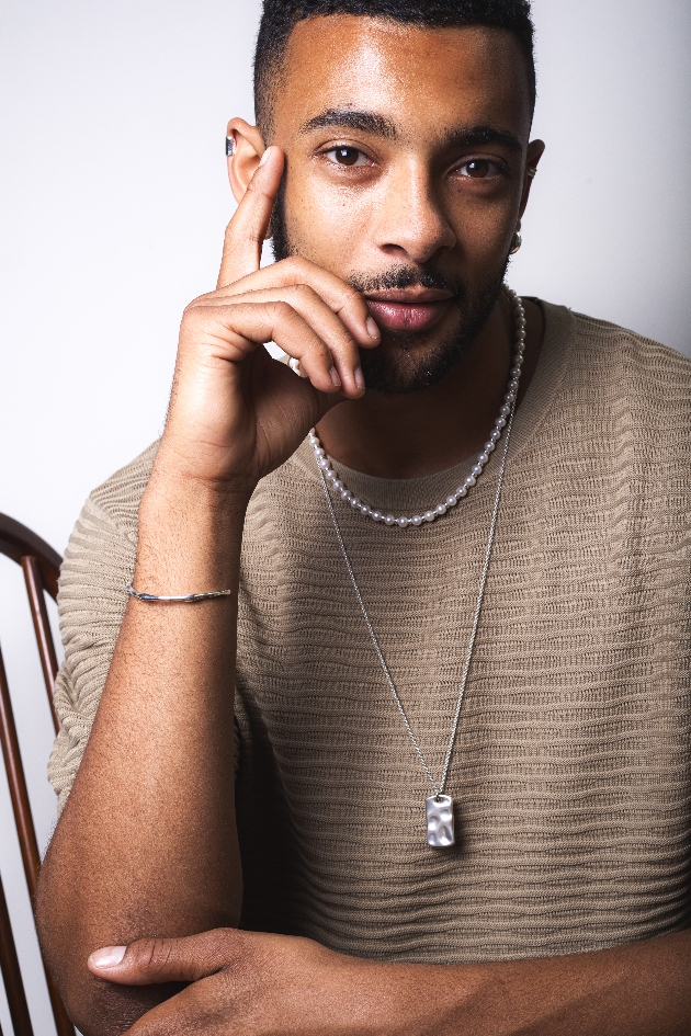 A man wearing two necklaces and a bracelet 